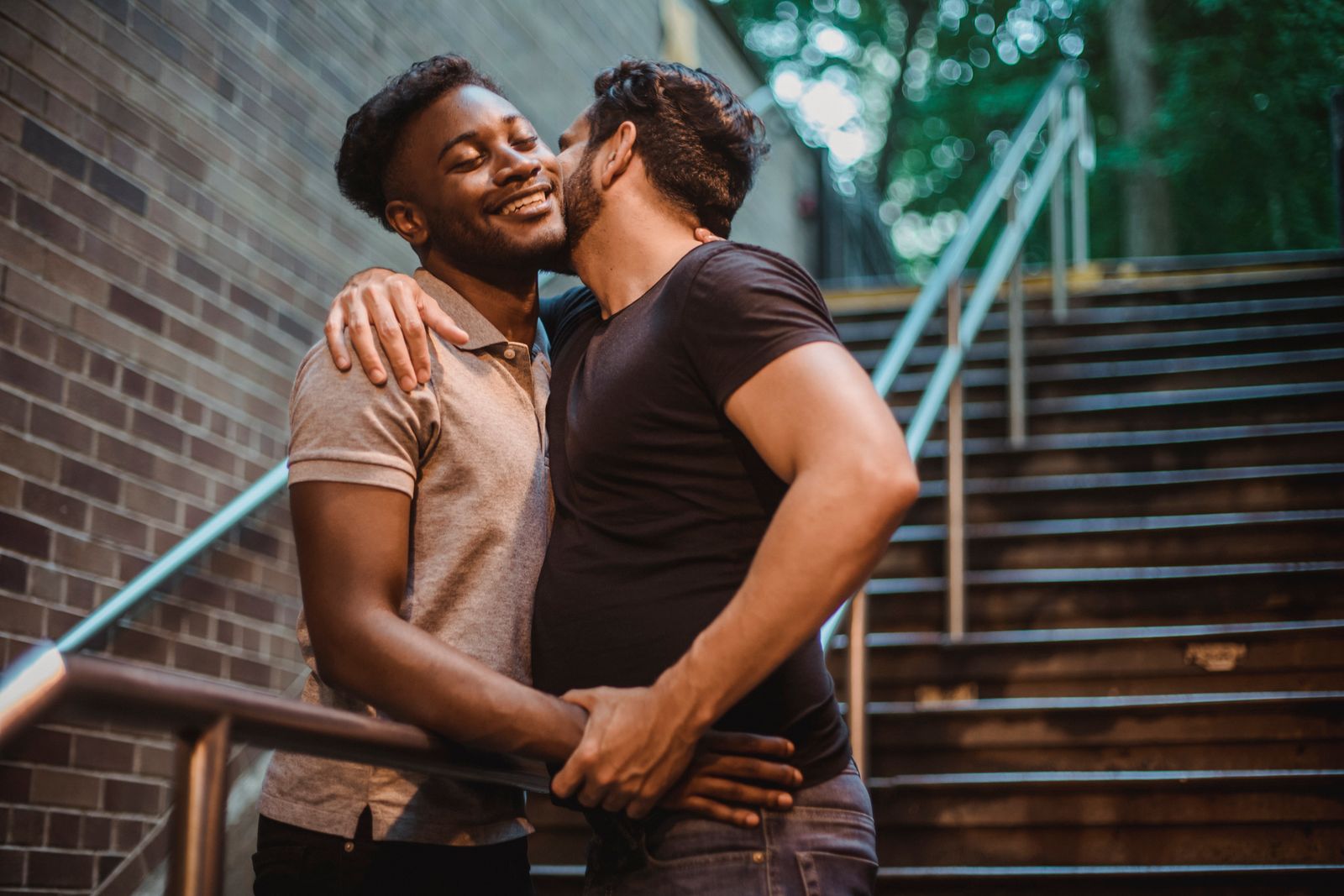 Un couple d’hommes enlacés et souriants dans un escalier