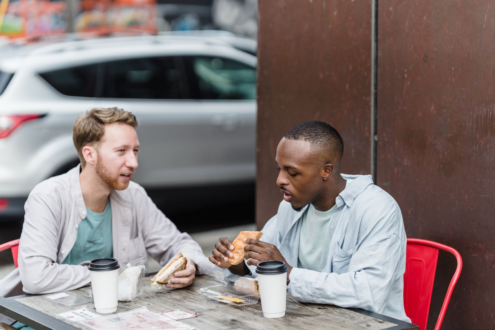 Two men chatting and smiling on a café terrace