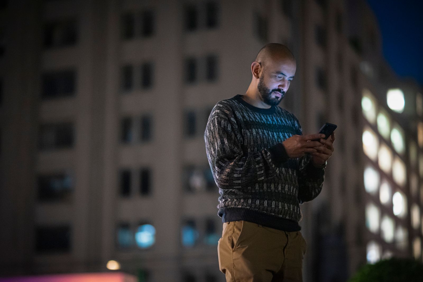 A man looks at his phone, alone in the dark
